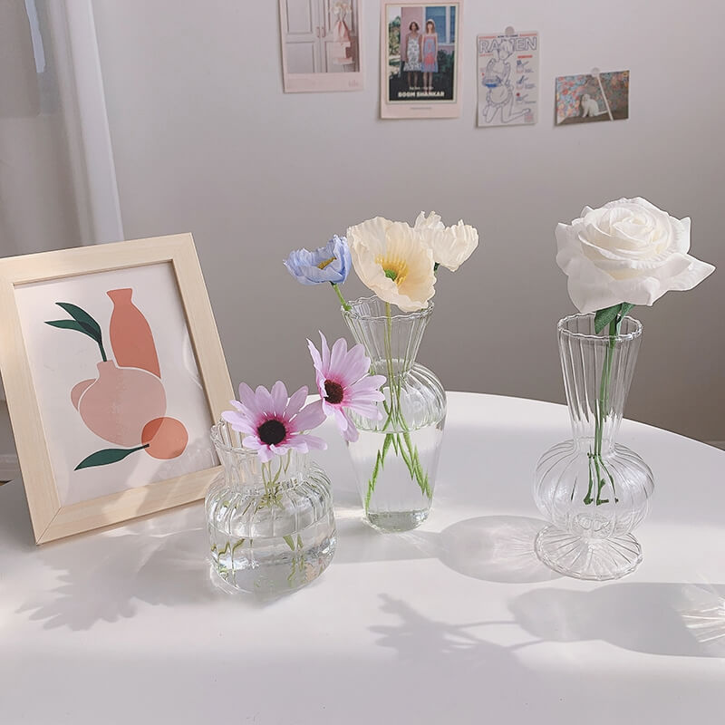 Flowers in glass vases on a table with framed art.