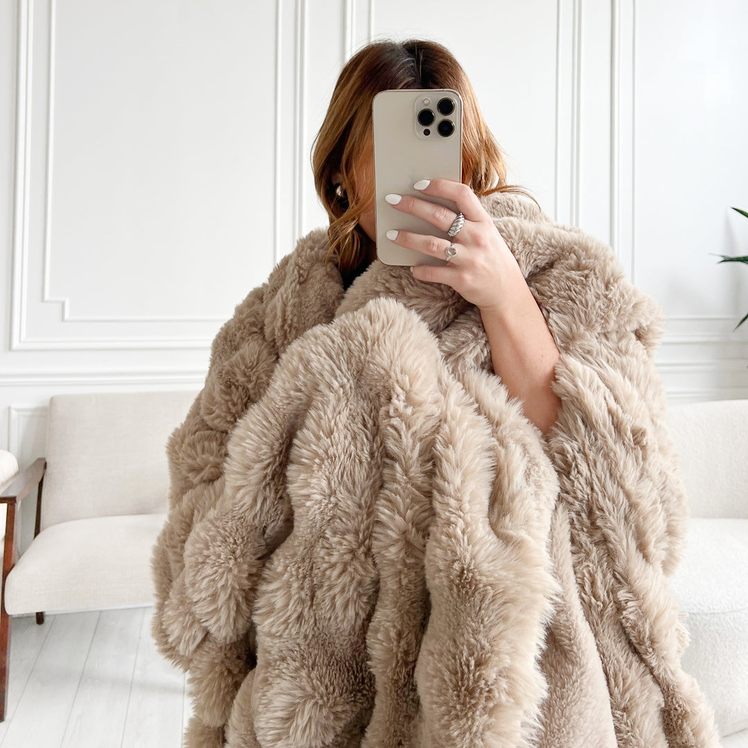 Woman in beige faux fur coat taking selfie