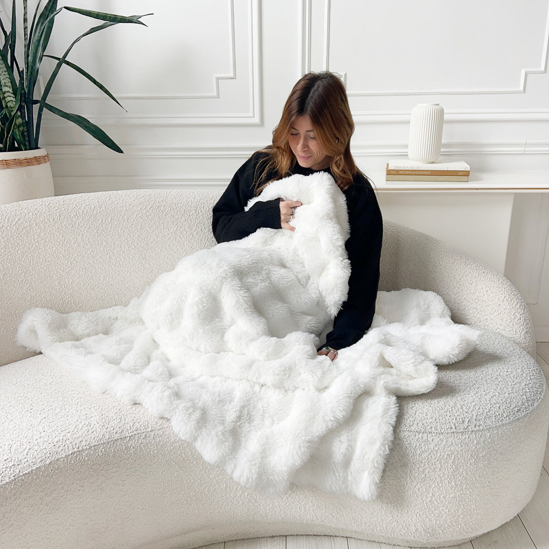 Woman with white fluffy blanket on couch